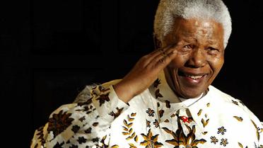 L'ancien président sud-africain Nelson Mandela salue une fanfare militaire à l'occasion de son 85e anniversaire à Johannesburg, le 18 juillet 2003 [Alexander Joe / AFP/Archives]