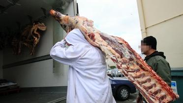 Un employé transporte une pièce de viande sous la surveillance d'un policier, dans un dépôt de boucherie, à Narbonne, le 16 décembre 2013 [Raymond Roig / AFP/Archives]