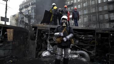 Un opposant, portant casque et masque à gaz, devant une barricade à Kiev, le 26 janvier 2014 [Aris Messinis / AFP]