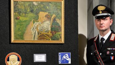 Un carabinier près d'un tableau de Pierre Bonnard, "la femme aux deux fauteuils", une des deux peintures volées à Londres dans les années 1970 et retrouvées en Italie, à Florence le 2 avril 2014 [Andreas Solaro / AFP]