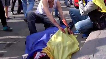 Capture d'écran provenant de la chaîne Inter, montratn un homme couvrant le corps ensanglanté d'un autre homme avec un drapeau ukrainien lors d'une manifestation, le 2 mai 2014 à Odessa  [- / AFP]