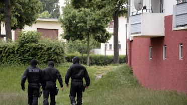 Un policier du RAID quitte l'immeuble d'un jihadiste présumé avec des documents, dans le quartier strasbourgeois de la Meinau, le 13 mai 2014 [Frédérick Florin / AFP]