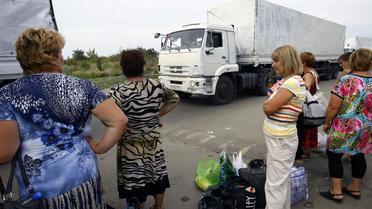 Des femmes observent les camions du convoi humanitaire envoyé par Moscou, au poste frontière d'Izvarino, entre la Russie et l'Ukraine, le 22 août 2014 [Sergey Venyavsky / AFP]