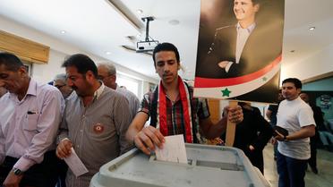 Un Syrien vote le 3 juin 2014 à Damas à l'élection présidentielle, devant une affiche du président sortant Bachar al-Assad, assuré de la victoire [Louai Beshara / AFP]