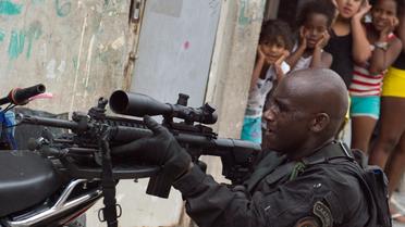 Des filles brésiliennes regardent un paramilitaire mener une opération de recherches d'armes dans une favela de Rio le 26 mars 2014 [Christophe Simon / AFP]
