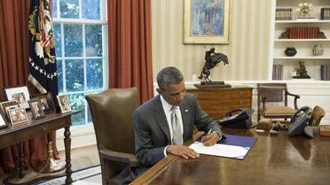 Le président américain Barack Obama signe un document prévoyant l'octroi de 225 millions de dollars supplémentaires à Israël pour le financement du Dôme de fer, le 4 août 2014 à la Maison Blanche [Saul Loeb / AFP]