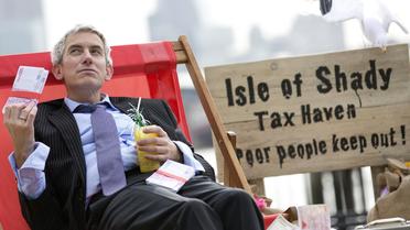 Un manifestant incarnant un banquier s'évente avec un liasse de faux billets, le 14 juin 2013 à Londres [Justin Tallis / AFP]
