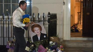 Un domestique dépose des fleurs en hommage à Margaret Thatcher devant le domicile de l'ex-Premier ministre britannique à Londres, le 8 avril 2013 [Will Oliver / AFP]