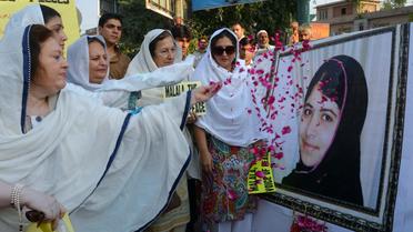 Des femmes lancent des pétales de rose sur le portrait de Malala Yusufzai, le 12 octobre 2012 à Peshawar [A. Majeed / AFP]