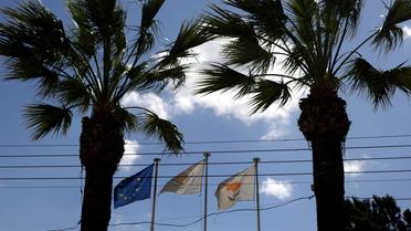 Le drapeau chypriote (d) flotte à côté de celui de la ville de Nicosie (c) et de l'Union européenne, le 23 mars 2013 [Patrick Baz / AFP]