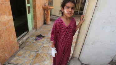 Une enfant, blessée, à l'entrée de sa maison à Bagdad, le 16 mai 2013, après un attentat à la voiture piégée [Ahmad al-Rubaye / AFP]
