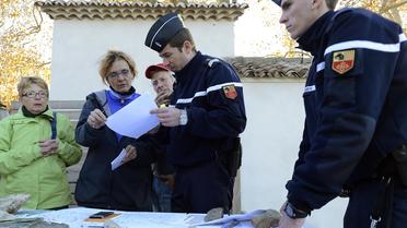 Des gendarmes et des volontaires examinent une carte le 12 novembre 2012 à Barjac lors de recherches pour retrouver une adolescente disparue [Boris Horvat / AFP]