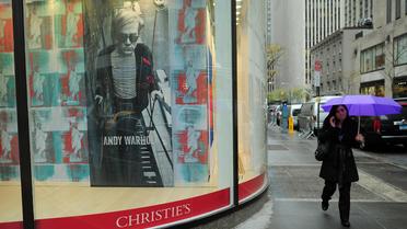 Une passante devant une affiche annonçant une vente aux enchères d'oeuvres d'Andy Warhol chez Christie's à New York, le 13 novembre 2012 [Emmanuel Dunand / AFP]