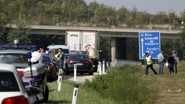 Des policiers autour du camion abandonné sur la bande d'arrêt d'urgence d'une autoroute dans lequel des corps en décomposition ont été découverts le 27 août 2015 près de Neusiedl am See en Autriche [DIETER NAGL / AFP]