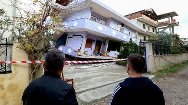Des Albanais observent une maison effondrée le 28 novembre 2019 à Durres sur la côte Adriatique après un séisme meurtrier [Gent SHKULLAKU / AFP]