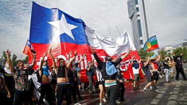Des manifestants agitant un drapeau géant chilien, à Santiago du Chili le 23 octobre 2019
 [Pablo VERA / AFP]