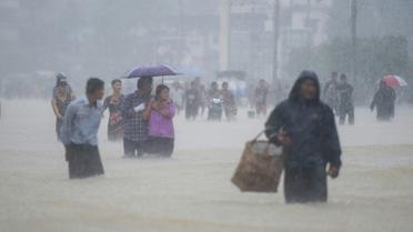 Des habitants de la ville de Pégou en Birmanie dans les rues inondées de leur ville, le 29 juillet 2018 [Ye Aung THU / AFP]