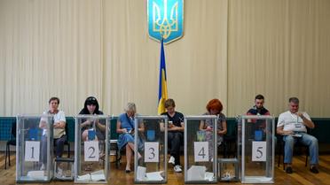 Des observateurs installés près des urnes dans un bureau de vote, lors des législatives, le 21 juillet 2019 à Kiev, en Urkaine [Sergei Supinsky / AFP]