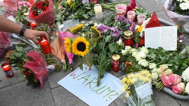Bougies, fleurs et note où est inscrit "Pourquoi" rendent hommage aux neuf victimes du forcené, à l'entrée du centre commercial de Munich le 23 juillet 2016 [Christof Stache / AFP]