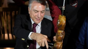 Le président brésilien Michel Temer lors d'un barbecue auquel des ambassadeurs étrangers étaient invités après une réunion  d'urgence sur le démantèlement d'un réseau de commercialisation de viande avariée au Brésil, le 19 mars 2017 à Brasilia [EVARISTO SA / AFP]