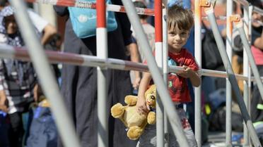 Son ourson à la main, un enfant de réfugiés attend le bus après son arrivée à Munich, le 1er septembre 2015 [CHRISTOF STACHE / AFP]