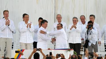 Le président colombien Juan Manuel Santos (G au centre serre la main du chef des Farc, Timoleon Jimenez, alias Timochenko (D au centre) scellant l'accord de paix historique [Luis ACOSTA / AFP]