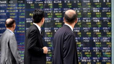 Des passants regardent un écran montrant des données boursières à Tokyo, capitale du Japon, le 24 juin 2016 [KAZUHIRO NOGI / AFP]