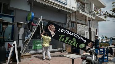Des employés travaillent à la réouverture d'un restaurant dans le port de Rafina, le 29 avril 2020, près d'Athènes, en Grèce [Louisa GOULIAMAKI / AFP]
