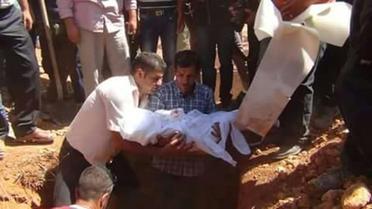 Le père du petit Aylan Kurdi (c) tient entre ses bras la dépouille de son fils avant son enterrement à Kobané en Syrie, le 4 septembre 2015 [STR / AFP]