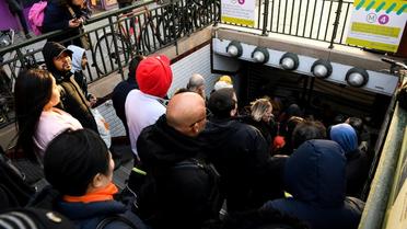 Des voyageurs attendent que les grilles du métro s'ouvrent le 20 décembre 2019 à la station Porte d'Orléans à Paris [Bertrand GUAY / AFP]