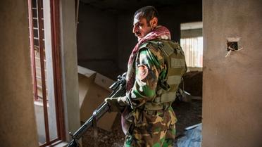 Un combattant peshmerga surveille des positions hostiles dans un immeuble de Bashiqa, le 9 novembre 2016 en Irak [Odd ANDERSEN / AFP]