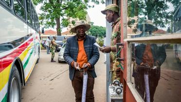 Un soldat contrôle des délégués à leur arrivée à une réunion cruciale du parti au pouvoir dimanche à Harare alors que le président Mugabe est lâché par ses principaux soutiens [Jekesai NJIKIZANA / AFP]