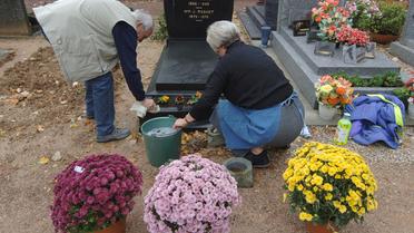 Un couple entretient la tombe d'un proche le 26 octobre 2006 dans un cimetière de Caen [Mychele Daniau / AFP/Archives]