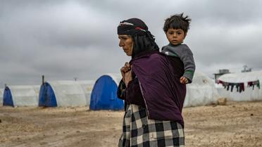 Une femme syrienne porte un enfant dans un camp pour déplacés, près de Hassaké, dans le nord-est de la Syrie en guerre, le 17 février 2020 [Delil SOULEIMAN / AFP]