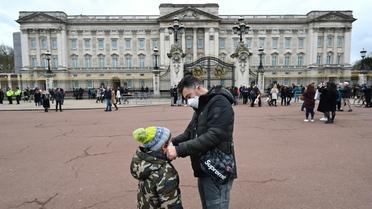 Un père ajuste le masque de protection de son fils, le 14 mars 2020 à Londres [Glyn KIRK / AFP]