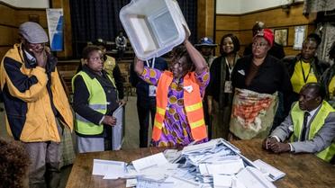 Un agent électoral renverse une urne lors des opérations de dépouillement des bulletins de vote pour les élections générales au Zimbabwe, le 30 juillet 2018 à Harare. [MARCO LONGARI / AFP]