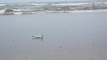 une bouteille renfermant un message échouée sur une plage / image d'illustration