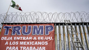 Un drapeau mexicain et une bannière indiquant «Trump, laissez les Mexicains entrer aux États-Unis pour travailler» à Playas de Tijuana, Mexique, le 2 février 2020. 