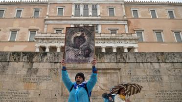 Des manifestants tiennent une peinture orthodoxe chrétienne alors qu'ils se rassemblent sous une pluie battante, devant le parlement grec à Athènes, le 25 janvier 2019, lors d'une manifestation contre le changement de nom signé avec la Macédoine voisine.