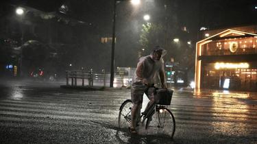 Un homme se déplace à vélo dans Tokyo, la capitale japonaise frappée par le typhon Faxai le 9 septembre 2019 [Charly TRIBALLEAU / AFP]