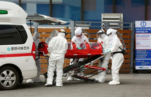 Du personnel médical en combinaison de protection transportent un malade atteint du COVID-19 dans un hôpital de Chuncheon, le 22 février 2020 en Corée du Sud [- / YONHAP/AFP]