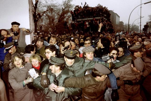 Des policiers est et ouest-allemands essaient de contenir la foule de Berlinois de l'Est qui passent à Berlin Ouest après l'ouverture des frontières, le 12 novembre 1989 [Patrick HERTZOG / AFP/Archives]