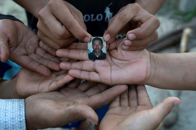 Une veuve et ses cinq enfants montrent le 23 juillet 2020 une photo de leur époux et père, Joaquin Barrera, mort du Covid-19 comme ses parents et deux de ses frères à Santiago Nonualco, au Salvador</p>
<p> [Yuri CORTEZ / AFP]
