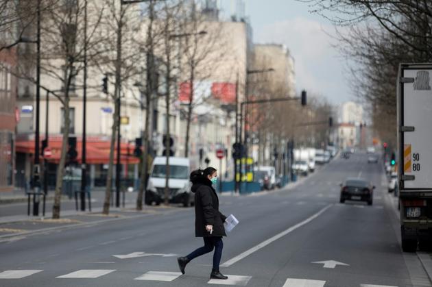 Une femme traverse une rue déserte, le 18 mars 2020 à Aubervilliers, près de Paris, pendant le confinement [Thomas SAMSON / AFP/Archives]