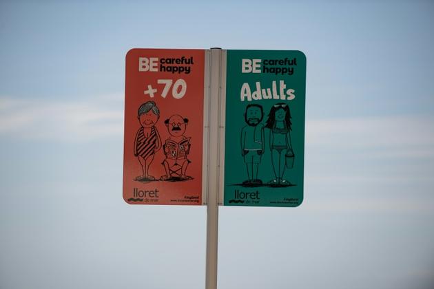 Un panneau indique les espaces réservés aux diffférents âges sur la plage de Lloret de Mar, le 22 juin 2020 en Espagne [Josep LAGO / AFP]