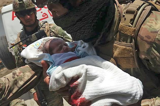 Un membre des forces de sécurité afghane porte un nouveau-né évacué d'un hôpital attaqué par des hommes armés, le 12 mai 2020 à Kaoul [STR / AFP]