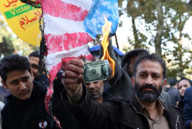 Un Iranien brûle un dollar lors d'une manifestation le 4 novembre 2018 à Téhéran marquant le 39e anniversaire de l'occupation de l'ambassade américaine [ATTA KENARE / AFP]
