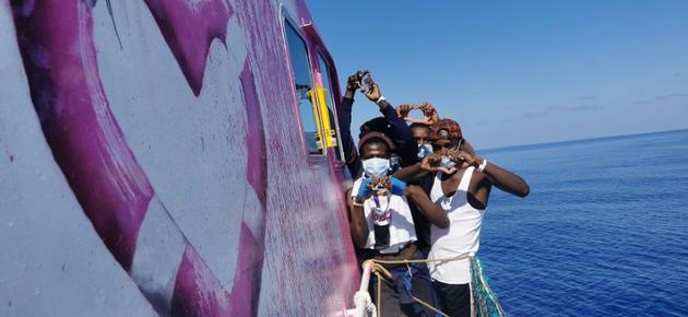 Image prise le 29 août 2020 sur le compte twitter @MVLouiseMichel. Des migrants font des coeurs avec les mains à bord du navire Banksy [- / Twitter account MVLouiseMichel/AFP]