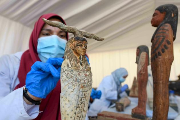 Une archéologue nettoie des statuettes en bois découvertes à Saqqara, lors d'une cérémonie, le 14 novembre 2020 [Ahmed HASAN / AFP]