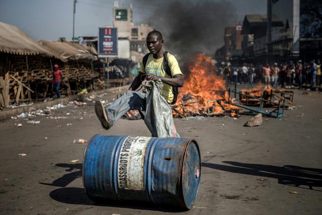 Un partisan de l'opposition au Zimbabwe pousse un bidon devant une barricade enflammée, le 1er août 2018 à Harare. [Luis TATO / AFP]